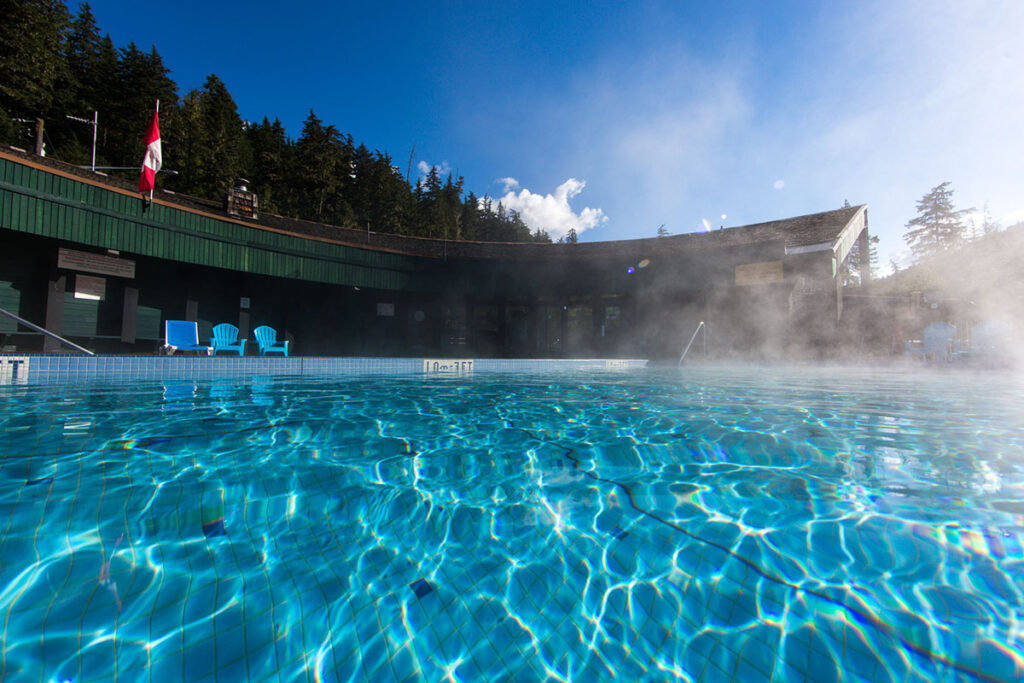 Steam rising off the pool at Nakusp Hot Springs with the cedar bathhouse behind